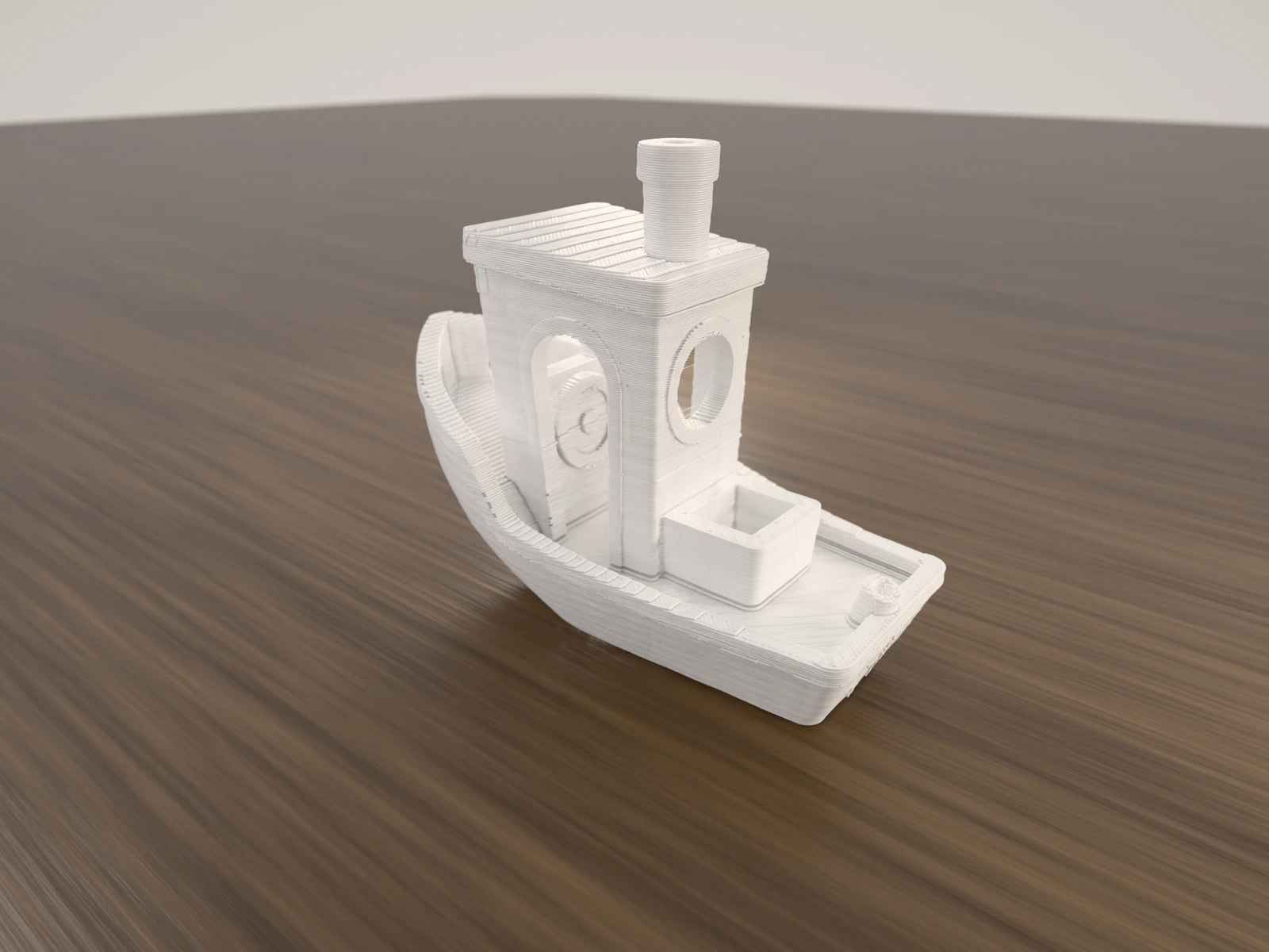 A white 3D-printed tugboat on a dark wood desk, layer lines visible along the hull, photographed under soft window light.